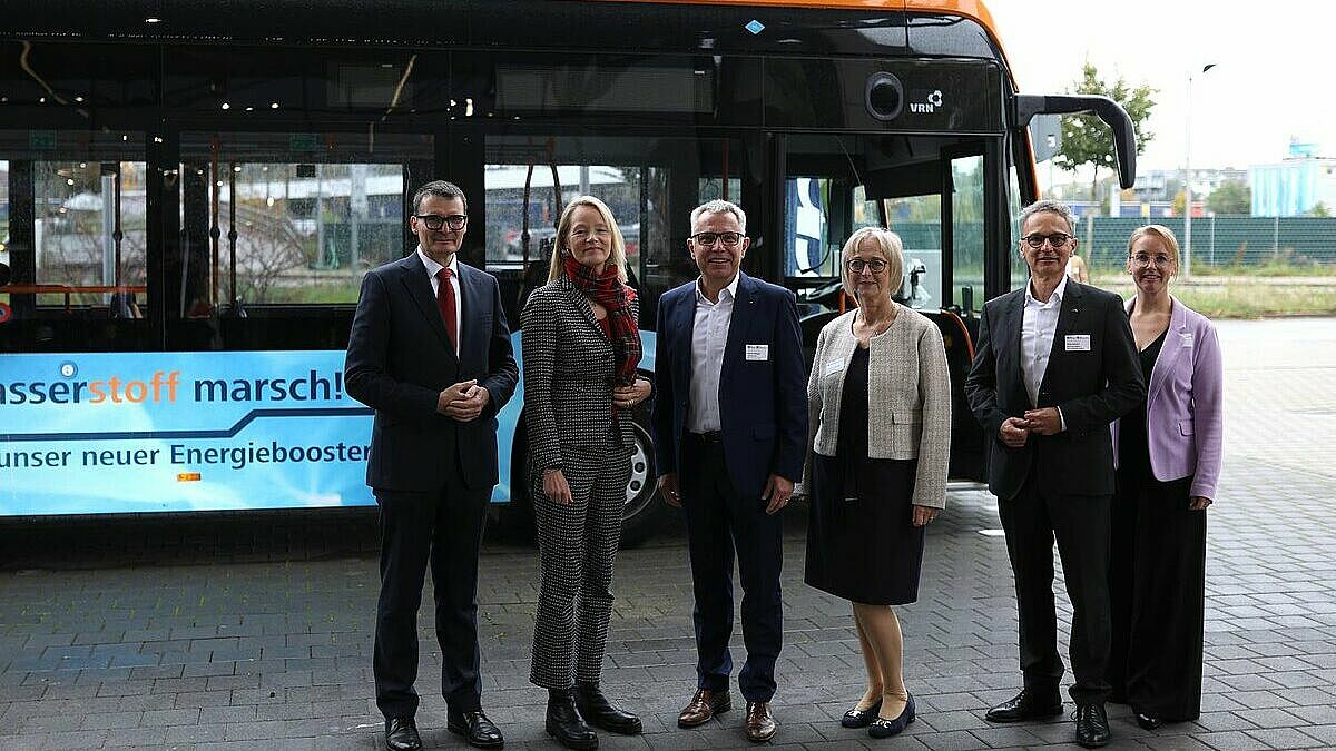 Vor einem Brennstoffzellenbus stehen Staatssekretär Höppner, Ministerin Walker und Beteiligte der MRN und e-mobil BW