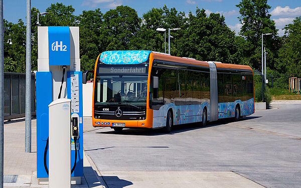 Ein Gelenkbus mit Brennstoffzellenantrieb fährt an eine Wasserstofftankstelle.